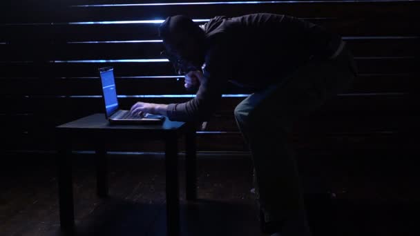 Cómico hacker divertido comete un ataque cibernético con un ordenador portátil y una pistola en sus manos — Vídeo de stock