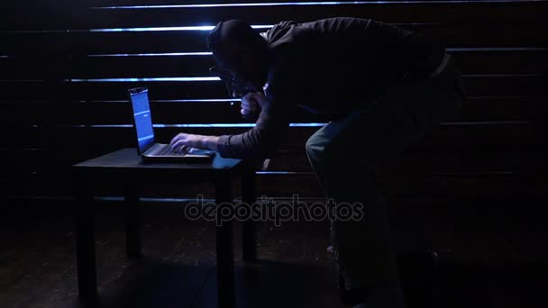 Comic funny hacker commits a cyber attack with a laptop and a gun in his hands — Stock Video