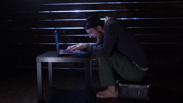 Комічний смішний хакер здійснює кібератаку з ноутбуком і пістолетом в руках — стокове відео