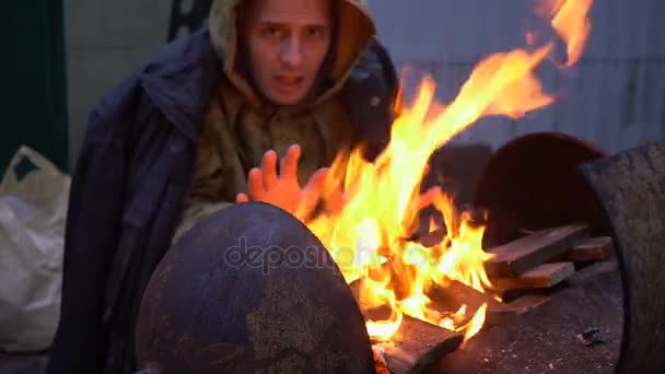 Porträtt av hemlös man framför en eld, närbild — Stockvideo