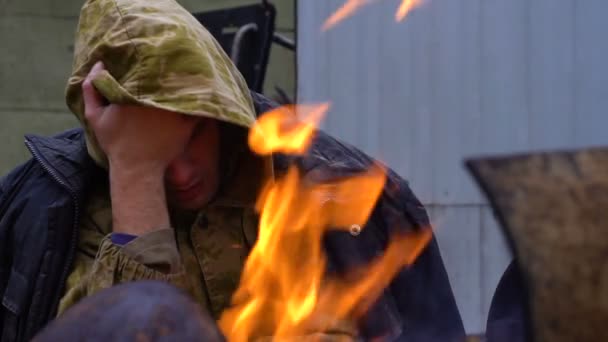 Печальный бездомный рядом с огнем — стоковое видео