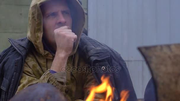 Печальный бездомный рядом с огнем — стоковое видео