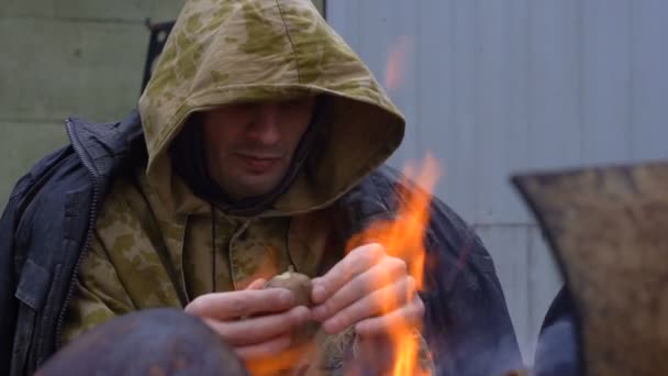 Hombre sin hogar comiendo junto al fuego clouse up — Vídeo de stock
