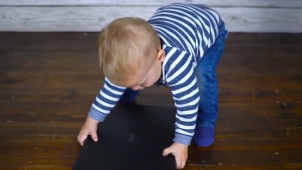 Das schöne einjährige Kind wird mit einem Laptop gespielt. Geschäftliches Konzept — Stockvideo