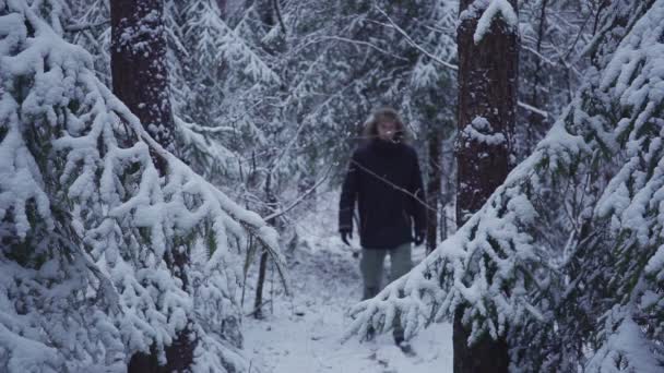 バックパック旅行雪冬の森を歩く男。カメラに手を振ってください。 — ストック動画