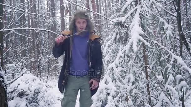 Lunch i vinter skog. En man äter en korv på en kvist — Stockvideo