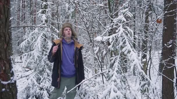 Almuerzo en el bosque de invierno. Un hombre come una salchicha en una ramita — Vídeos de Stock