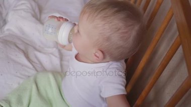 Ayakta ve bir şişe süt içme gülümseyen erkek bebek