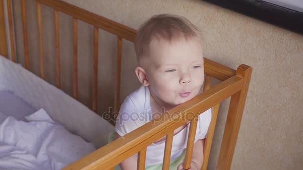 Kid in the crib looks around speaks, jumps and smiles. — Stock Video