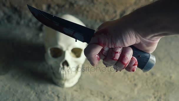 Killer galning med en kniv på bakgrunden av skallen. Blodiga Hand. dödande koncept — Stockvideo