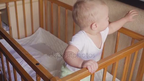 Dziecko w niemowlęcym rozgląda się mówi, skacze i uśmiecha się. — Wideo stockowe