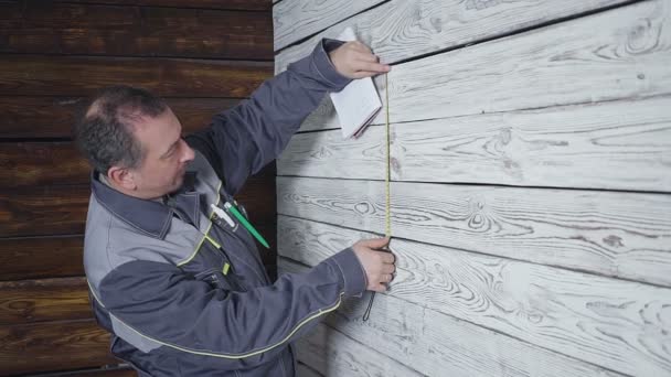 Працівник вимірює дерев'яну стіну з лінійкою — стокове відео