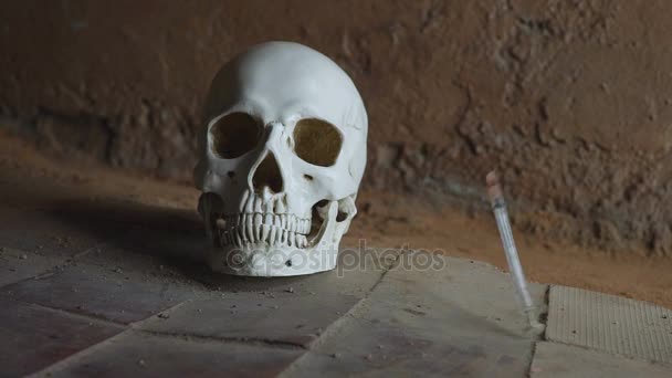 Syringe falling down spraying blood after a heroin cocaine injection against the background of the skull — Stock Video