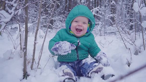 Cheerful one year boy is sitting in the winter forest and laughs. created with gimbal — Stock Video