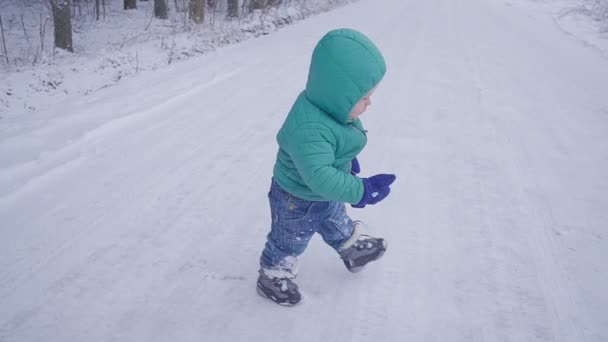 Vrolijke eenjarige jongen in de winter bos weg. gemaakt met gimbal — Stockvideo