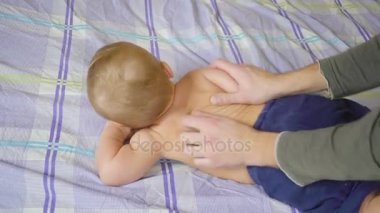 Baba ile bebek bebek yatakta masaj vücut yapıyor. Sağlıklı bir yaşam tarzı. Ağır çekim
