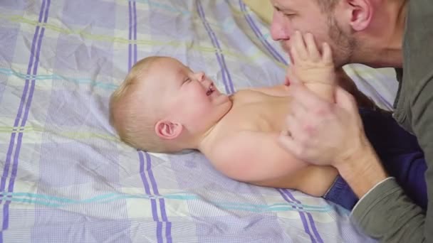 Батько цілує, обіймає і лоскоче свого маленького сина . — стокове відео