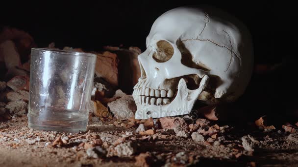 Man pours alcohol and drinks on the background of the skull. alcohol addiction cincept. 4k — Stock Video