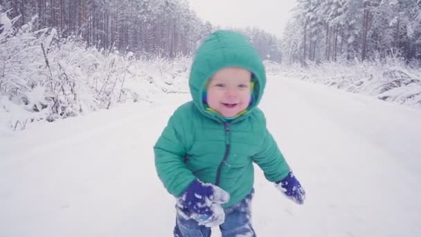 Vrolijke eenjarige jongen in het bos van de winter. gemaakt met gimbal — Stockvideo