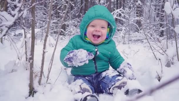 Neşeli bir yıl çocuk içinde belgili tanımlık kış orman ve gülüyor oturuyor. yalpa ile oluşturulan — Stok video