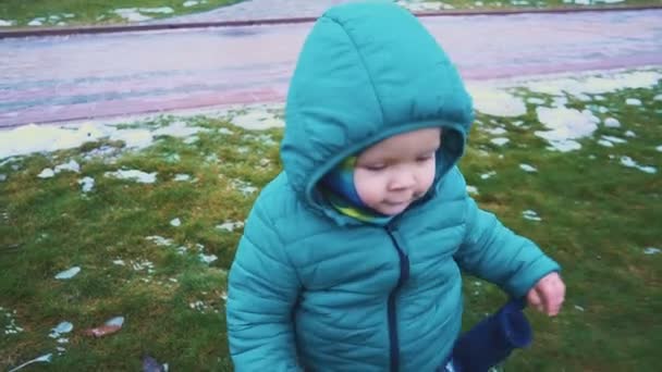 Bahar. Steadicam vurdu kaldırımdan çalışan çocuğu, çim ve eriyen kar. ağır çekim — Stok video