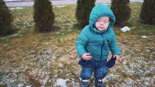 Primavera. Steadicam tiro de niño corriendo por la acera, hierba y nieve derretida. cámara lenta — Vídeo de stock