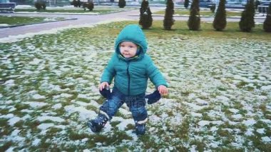 Bahar. Steadicam vurdu kaldırımdan çalışan çocuğu, çim ve eriyen kar. ağır çekim
