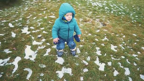 Την άνοιξη. παιδί τρέχει κάτω από το πεζοδρόμιο, το χόρτο και το χιόνι λιώνει. — Αρχείο Βίντεο