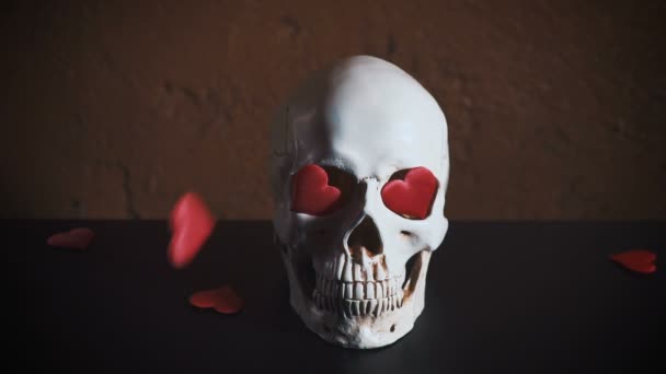 Menschlicher Schädel mit rotem Herzen. Herzen fallen auf den Schädel in Zeitlupe. Konzept für Valentinstag. — Stockvideo