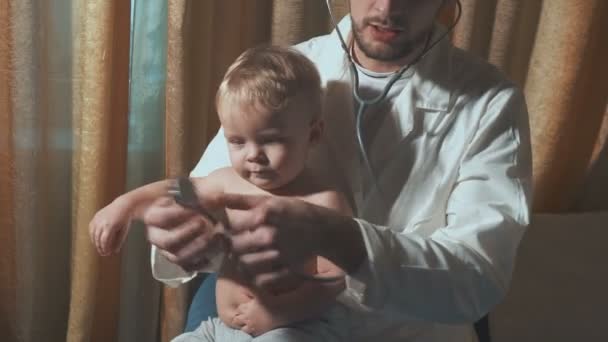 Le médecin rend visite au bébé patient à la maison. Bébé avec stéthoscope — Video