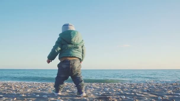 Lifestyle van de baby. De jongen rent bij zonsondergang naar zee. vakantie concept. Langzame beweging — Stockvideo