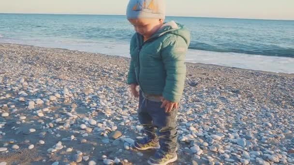 Bebeğin bir yaşam tarzı. Bir çocuk bir doğal plajda kum ve taş ile oynanır. stedicam ile vurdu — Stok video