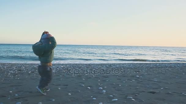 Ein einjähriger Junge rennt und spielt am Strand in der Nähe des Meeres — Stockvideo