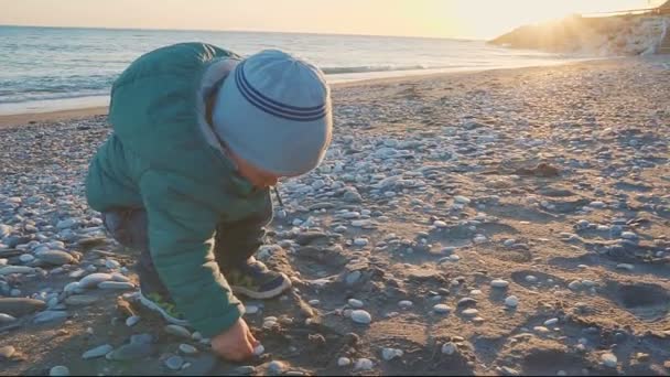 Života dítěte. Chlapec se hraje s pískem a kameny na přírodní pláž — Stock video