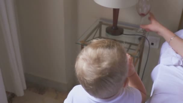 Een één-jarige jongen drinkt melk, en zijn moeder drinken wijn. Het concept van een disfunctionele familie en alcoholisme — Stockvideo