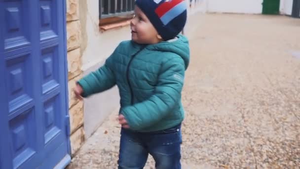 ジャケットに小さな男の子を中庭では、パスに沿って実行ヤード。スローモーション — ストック動画