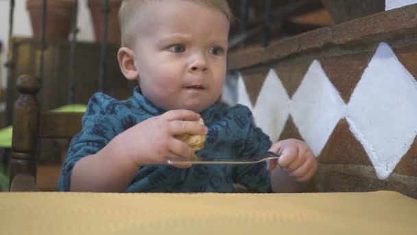 Baby boy eet brood in een restaurant — Stockvideo