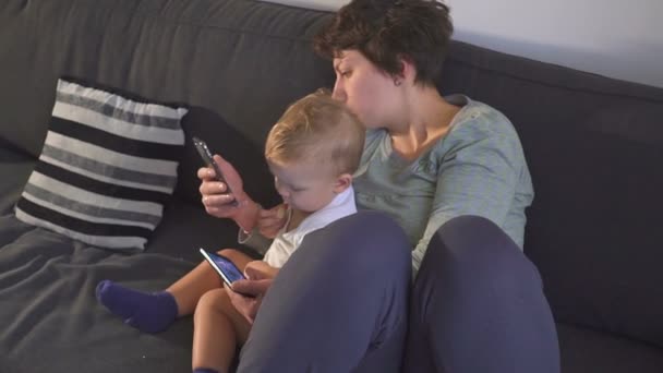 Mother and son are looking at their smartphones. Gadget addiction concept. — Stock Video