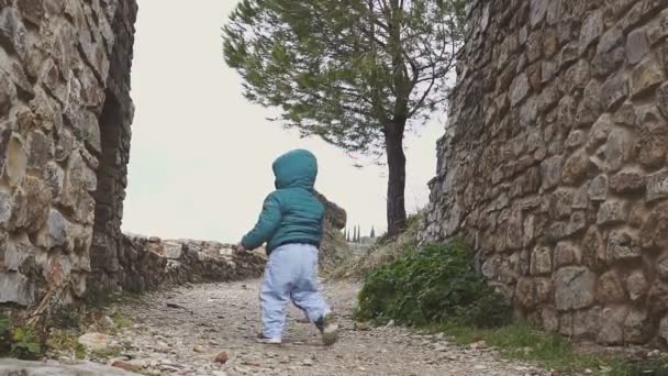 Bebé de un año camina cerca de las ruinas viejo castillo en las montañas. España. Ronda — Vídeo de stock