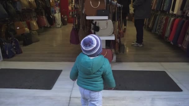 Chico de un año está considerando una tienda. El chico examina cuidadosamente el interior de la tienda. Movimiento lento — Vídeo de stock