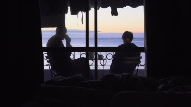 Balcon dans l'hôtel avec vue sur la mer. Une jeune femme et un homme regardent le lever du soleil — Video