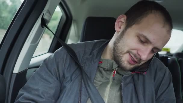 Primer plano joven hablando en el teléfono móvil mientras monta en el asiento trasero del coche — Vídeos de Stock