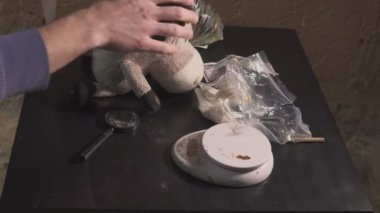 Uyuşturucu satıcısı uyuşturucu - eroin, kokain - paketleri paketleri ve onları ağırlığındadır. O uyuşturucu saklandığı yerden alır ve para koyar bir saklanma yeri. Yasadışı uyuşturucu bağımlılığı kavramı.