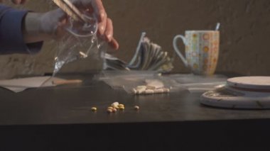 Uyuşturucu satıcısı uyuşturucu - tablet amfetamin veya diğer - paketleri paketleri ve onları tartmak.