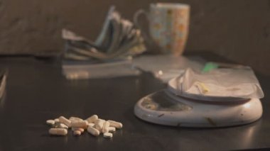 Uyuşturucu satıcısı uyuşturucu - tablet amfetamin veya diğer - paketleri paketleri ve onları tartmak.