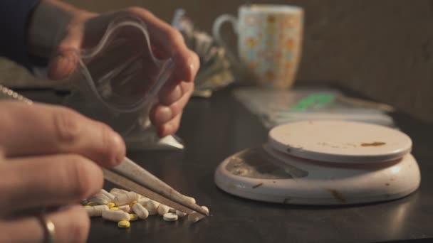 Наркоторговец упаковывает наркотики - в таблетки амфетамин или другие - в пакеты и взвешивает их . — стоковое видео