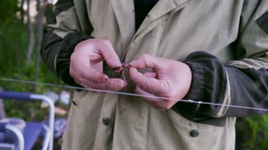 balıkçı kanca çubuk üzerinde balık için yem olarak solucanlar koyar