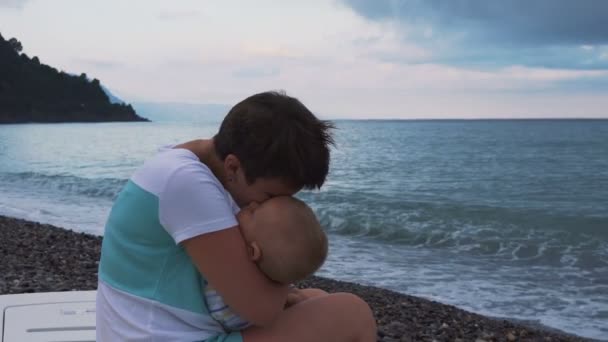 Sover barnet i mammor händer på stranden — Stockvideo