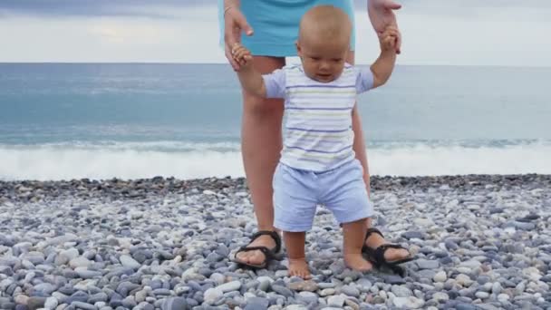 Un niño pequeño está jugando y caminando con su madre en la playa — Vídeo de stock