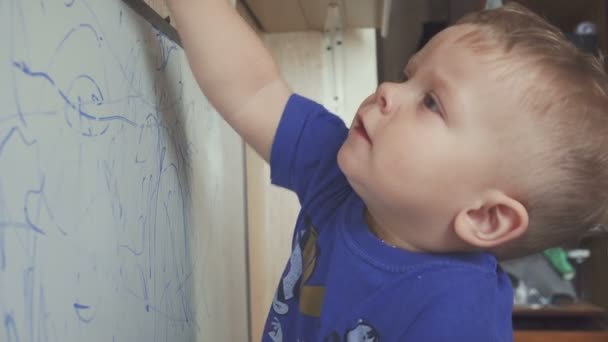 Baby sitzt auf dem Fensterbrett und zeichnet auf Markierungsplatte. — Stockvideo